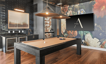 A pool table in a room with a brick wall and a TV mounted on the wall.